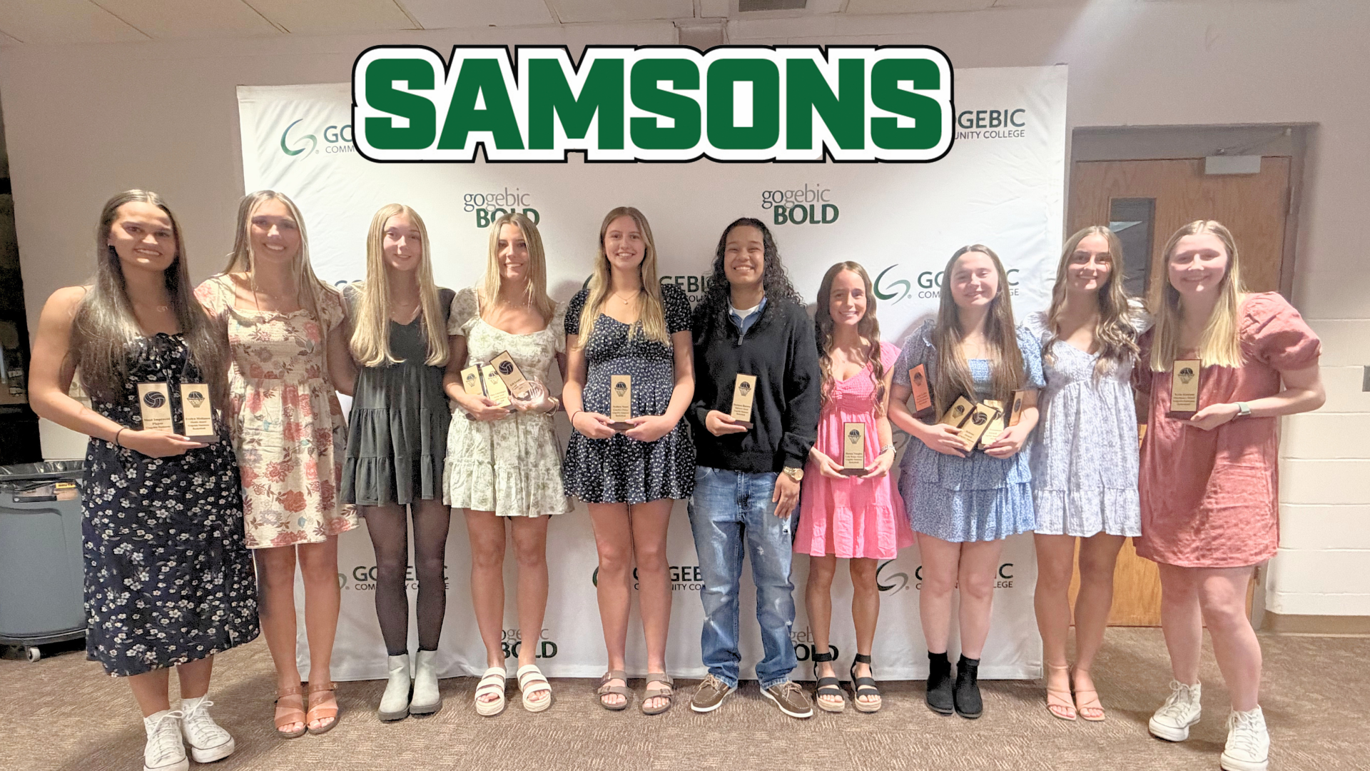 A group of women athletes standing in a line, holding their awards.